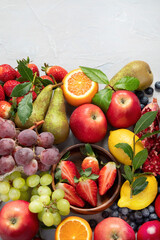 Assortment of colorful ripe tropical fruits on light gray background.
