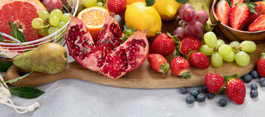Assortment of colorful ripe tropical fruits on light gray background.