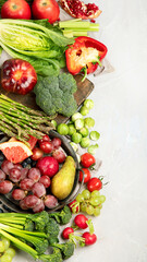 Delicious raw fruits and vegetables on light background.