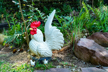 Decoration rooster statue with chick in the garden. White decorative cock sculpture with brood of...