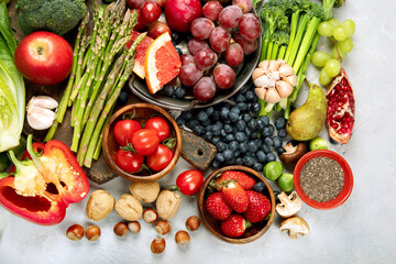 Delicious raw fruits and vegetables on light background.