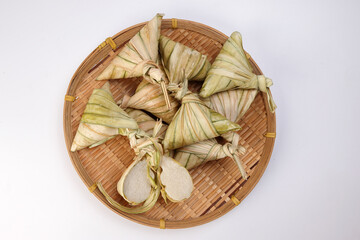 Traditional diamond shaped woven palm leaf pouch steamed glutenous rice cake ketupat kupat tipat on bamboo tray white background