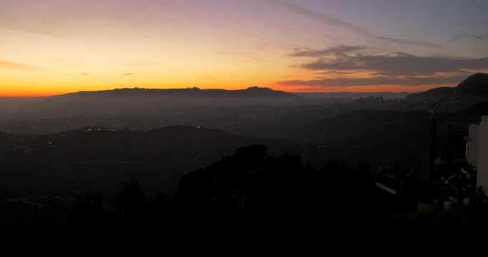 View of colorful sky at sunset from Griffith observatory, Los Angeles, USA. Beautiful hilly terrain under orange sky. 4K.