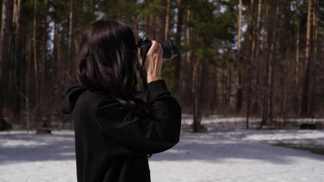 girl photographer takes pictures in the forest. woman holding a camera