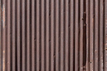 A view of old rusty sheet metal surface with corrugated texture, as a background.