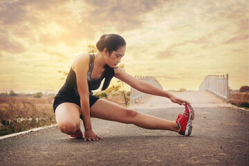 Young woman runner warming up at the roadtrack. Fit runner workout, stretch her muscle and warming...