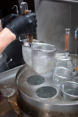 A view of a hand using ramen noodle strainers.
