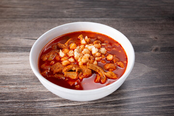 A view of a bowl of menudo with hominy topping.