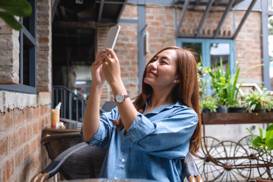 Portrait image of a beautiful young asian woman using mobile phone to take a photo in cafe