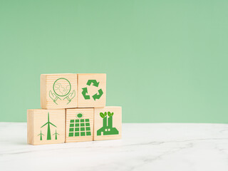 Net-zero greenhouse gas emissions target. Wooden cubes with green icons over a marble floor against a light green background