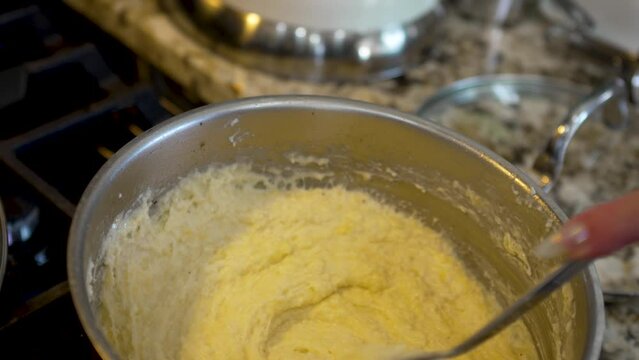 Stirring a sauce pan full of creamy, cheesy grits - shrimp and grits meal