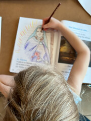 Selective focus of top of young girl's head with a blurred biblical drawing being colored below.