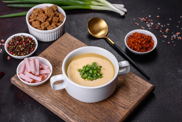 Cream soup with potatoes, leek and peas on a dark concrete table