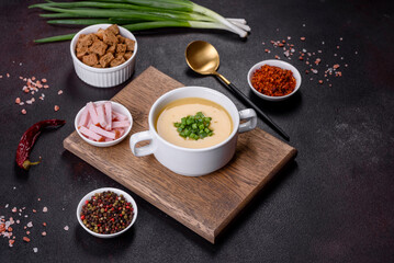Cream soup with potatoes, leek and peas on a dark concrete table