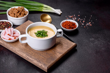 Cream soup with potatoes, leek and peas on a dark concrete table