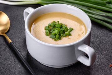 Cream soup with potatoes, leek and peas on a dark concrete table