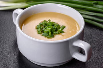 Cream soup with potatoes, leek and peas on a dark concrete table