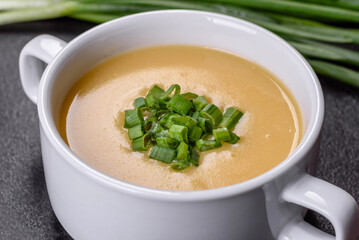 Cream soup with potatoes, leek and peas on a dark concrete table