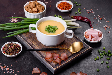 Cream soup with potatoes, leek and peas on a dark concrete table