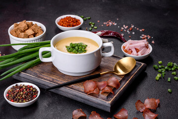 Cream soup with potatoes, leek and peas on a dark concrete table