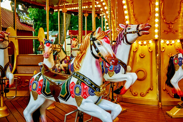 Carousel with colorful horses at amusement park, Merry go round with horse, Vintage ride attraction...