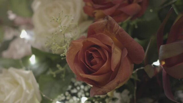 close crop shot of a flower bouquet with pink and white roses green leaves, sprigs, handheld, nostalgic and color faded look
