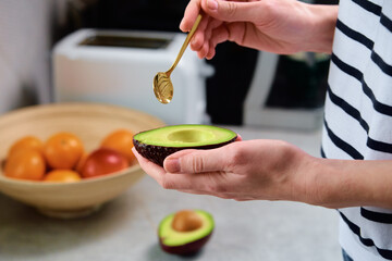 Woman hold fresh ripe avocado and peeling it with spoon, Healthy food and dieting concept, Organic product