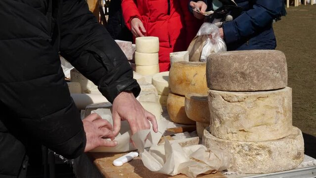A middle-aged farmer couple sells artisan cheeses at a local farmer's market. Family owned business