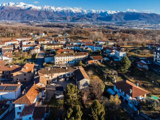 Central Friuli villages seen from above. Between hills and snow-capped mountains. Martinazzo of Cassacco.