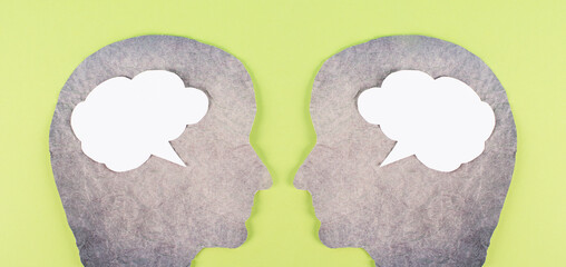 Silhouette of two faces, speech bubble in white color, copy space for text, communication, having an opinion and discussion, free speech, people talking, green background
