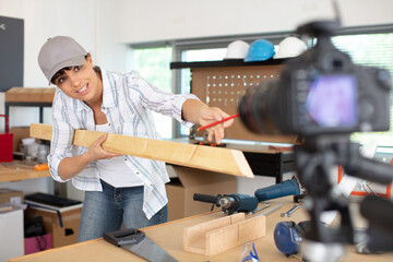 female carpenter filming in workshop for blog - obrazy, fototapety, plakaty