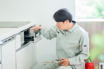 IH調理器（グリル）をチェックする作業着の男性（故障）
