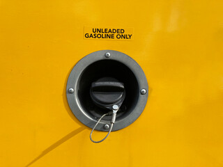 Unleaded gasoline only label above closed gas cap with metal tether