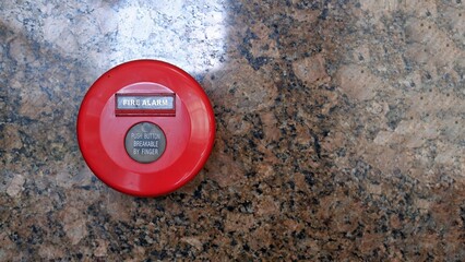 Red colour of manual fire alarm button activation in marble wall background, fire detection and...