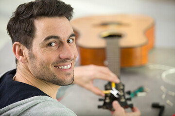 a handsome repairman repairing guitar