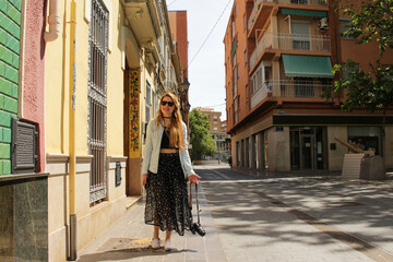 Tourist woman walking in the street with a camera 