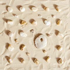 Pattern with one big stone with hole and many small on fine sand backgrund. Natural happy stone light ivory color. Symbol of fun, fortunate, lucky.