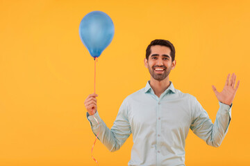 Portrait of happy young man holding balloon in hand and gesturing with palm © IndiaPix