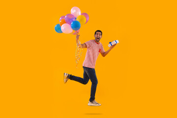Fototapeta na wymiar Happy young man flying with air balloons with gift in hand