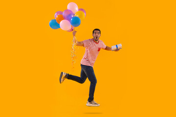 Fototapeta na wymiar Happy young man flying with air balloons with gift in hand