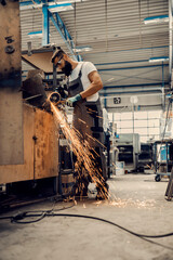 A heavy industry worker using grinder at workshop.