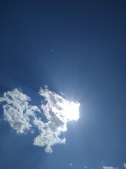 the sun is behind a small dot in the blue sky