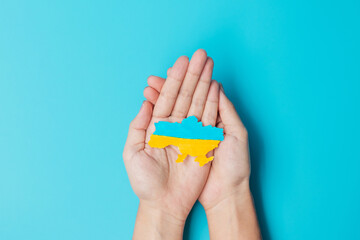 Support for Ukraine in the war with Russia, Hands holding the shape of Ukraine border with color flag. Pray, No war, stop war and stand with Ukraine