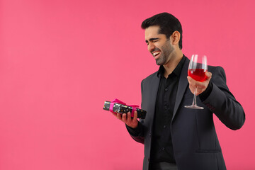 Portrait of happy businessman holding gift and wine glass in hands
