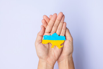 Support for Ukraine in the war with Russia, Hands holding the shape of Ukraine border with color flag. Pray, No war, stop war and stand with Ukraine