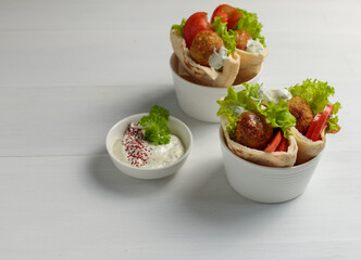 Two servings of mini pita with falafel .vegetables and sauce. On a light wooden background. Street food