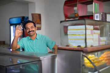 Fototapeta premium Portrait of happy Sweet shop owner standing at counter
