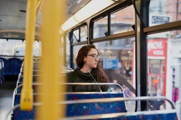 Shes on her way. High angle shot of an attractive young woman listening to music while sitting on a bus.