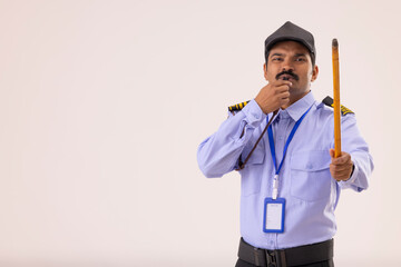 Portrait of Security guard blowing whistle with stick in his hand