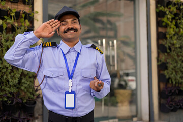 Portrait of security guard saluting while working at gate